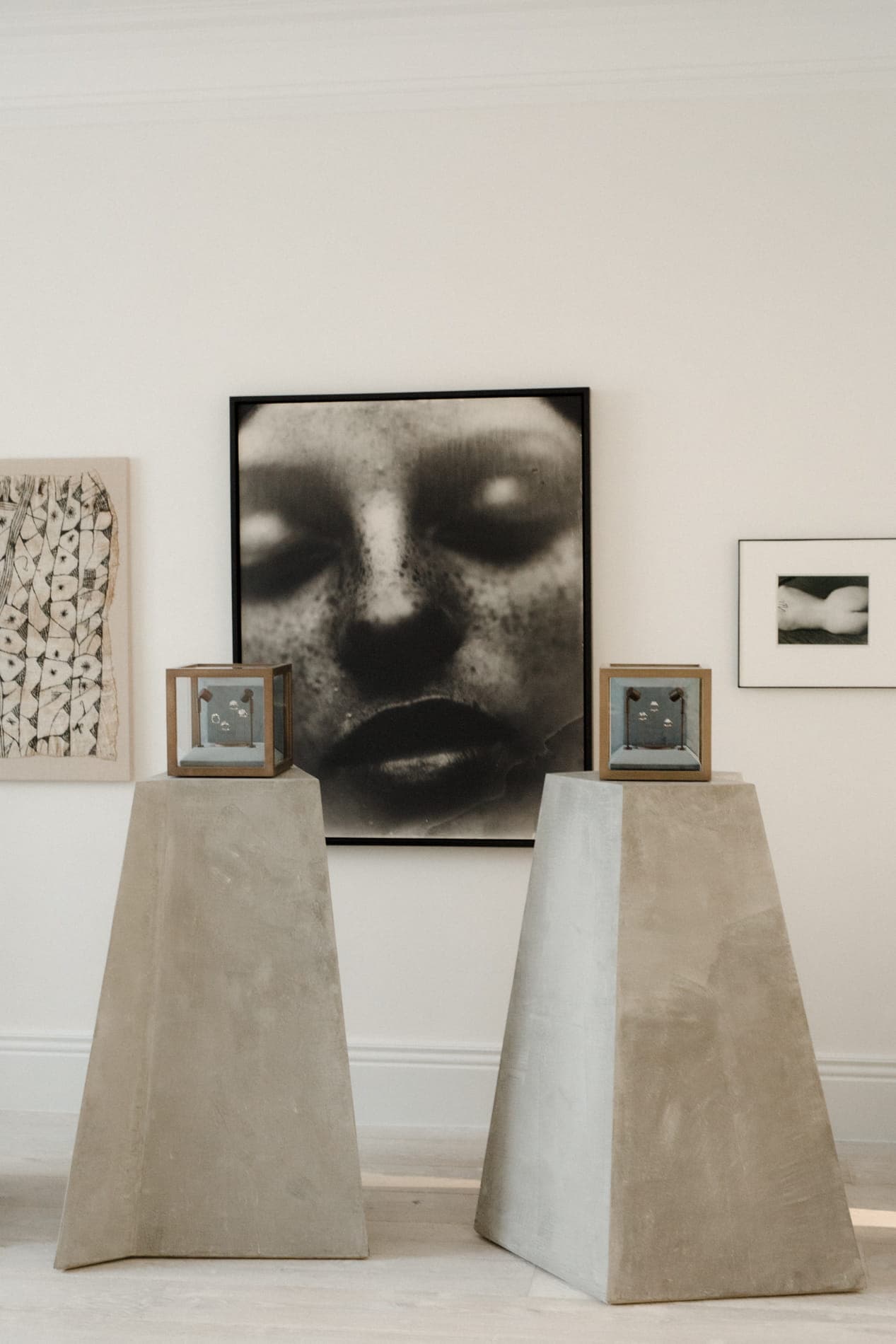 Art-led interior with framed black and white portrait, sculpted plinths and works on paper